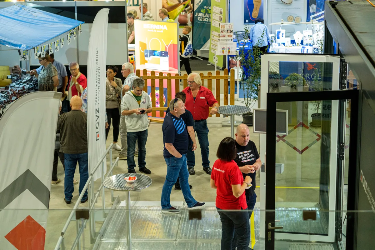 Menschen, die durch eine Messehalle laufen.